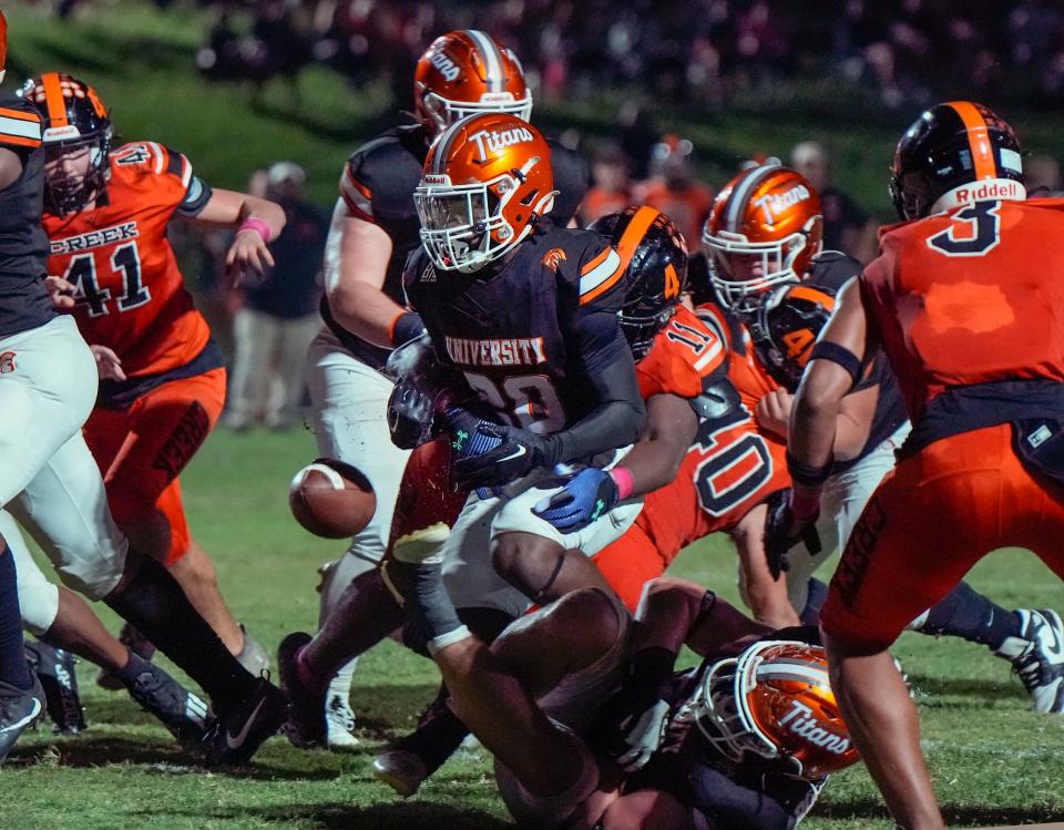 University's Jabailey Morris (20) fumbles ball after getting hit by Spruce Creek defense during a game at University High School in Orange City, Friday, Oct. 13, 2023.