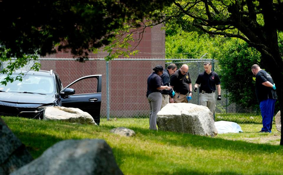 Medical examiners and police officers attend to the aftermath of Wednesday's shooting of a double-murder suspect.