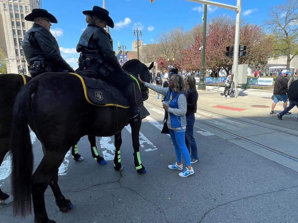 A group of NFL draft attendees stop to pet Wayne County Sheriff's Office horses Hogan, right, and Ace, left, on Thursday, April 25, 2024 along Woodward Avenue.