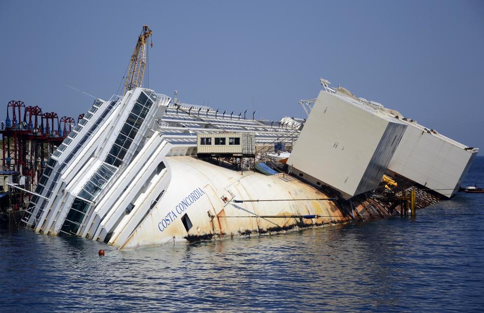 The Costa Concordia cruise ship lies on its side in the Tuscan Island of Isola del Giglio, Monday, July 15, 2013. Salvage crews are working against time to right and remove the shipwrecked Costa Concordia cruise ship, which is steadily compressing down on itself from sheer weight onto its granite seabed perch off the Tuscan island of Giglio. Salvage master Nick Sloane said Monday that the Concordia has compressed some 3 meters (10 feet) since it came to rest on the rocks Jan. 13, 2012 after ramming a jagged reef during a stunt ordered by the captain that cost the lives of 32 people. (AP Photo/Gregorio Borgia)