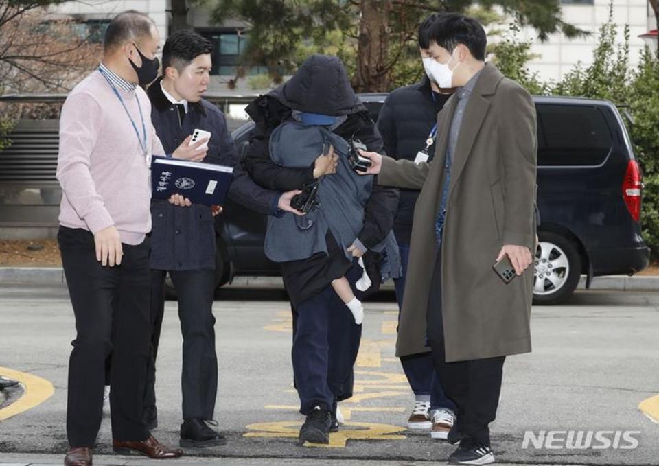 A女抱著小孩走向法院，面對記者詢問默默不語。（翻攝spotvnews網站）