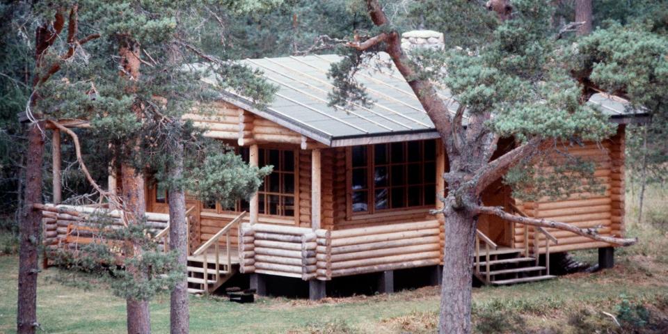 A large log cabin viewed through trees at Balmoral.