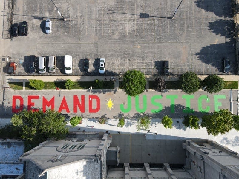 Community members paint the words "Demand Justice" outside the Faith Community of Saint Sabina on Chicago's South Side on July 1, 2020.