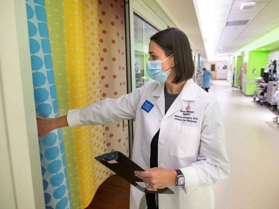 doctor in mask, coat, walking into patient room