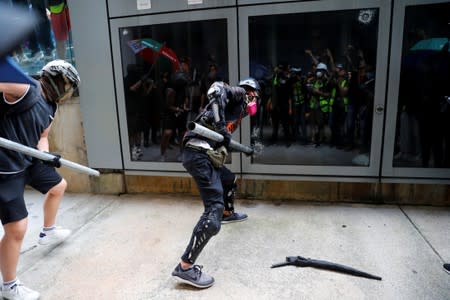 Anti extradition bill protestors try to break glass doors outside the terminals at Hong Kong International Airport, in Hong Kong