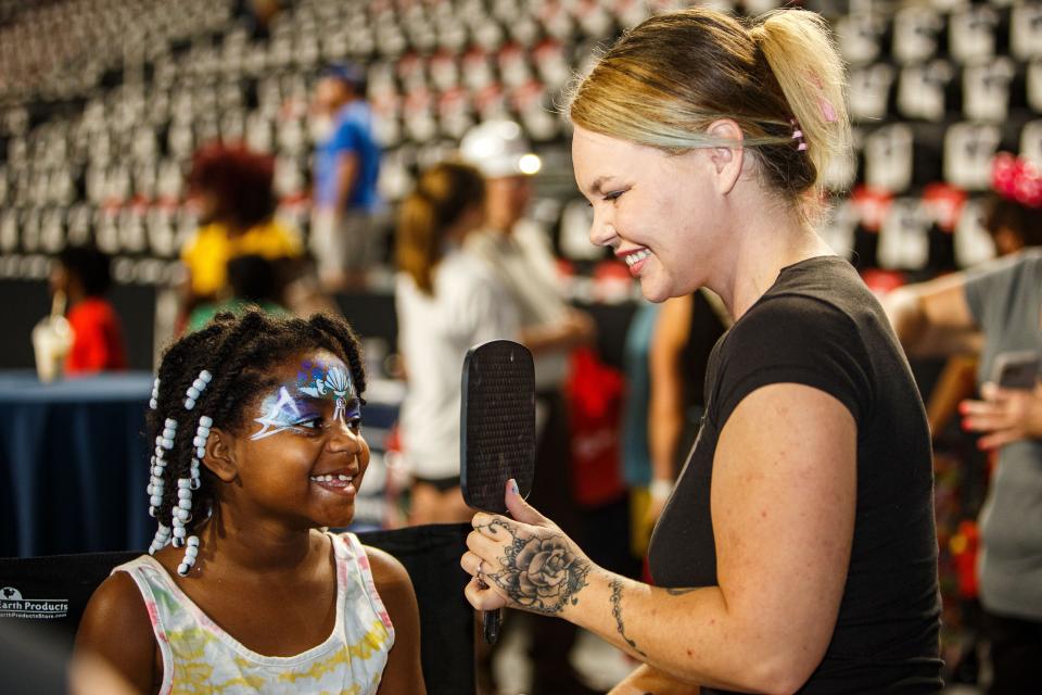 Aubrianna Cherry looks in a mirror after having her face painted by Rikki Fowler during the grand opening of F&M Bank Arena in Clarksville, Tenn. on Saturday, July 15, 2023.