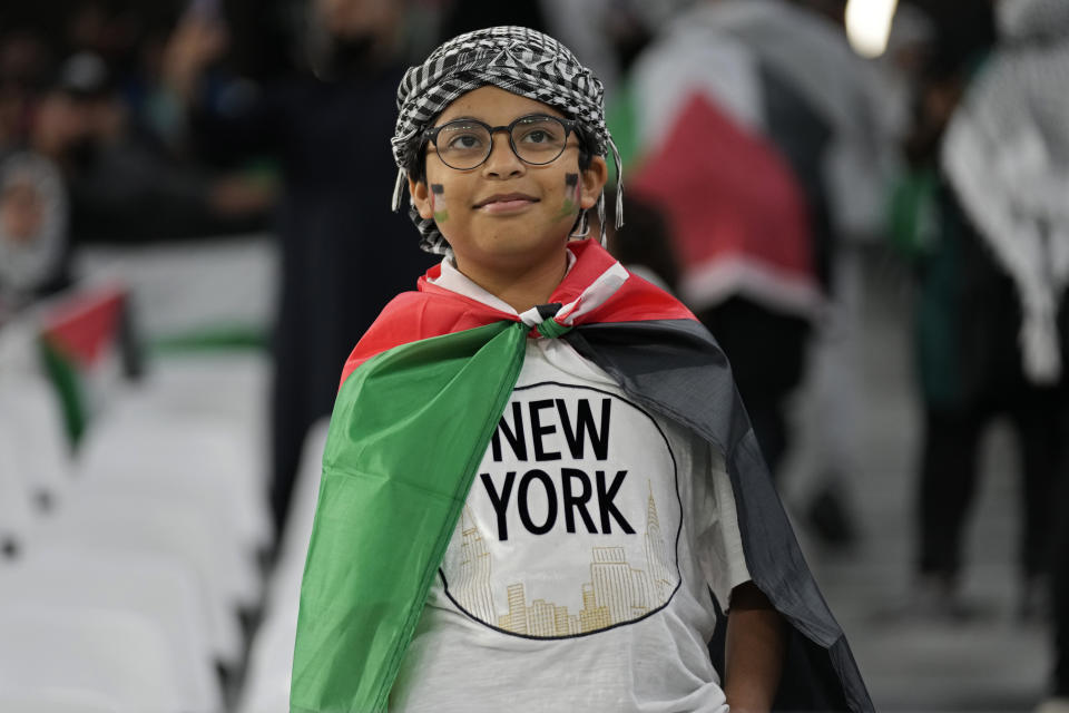 A young fan wears a Palestinian keffiyeh, a traditional Arab headdress, as he waits for the start of the Asian Cup Group C soccer match between Iran and Palestine at the Education City Stadium in Al Rayyan, Qatar, Sunday, Jan. 14, 2024. (AP Photo/Aijaz Rahi)