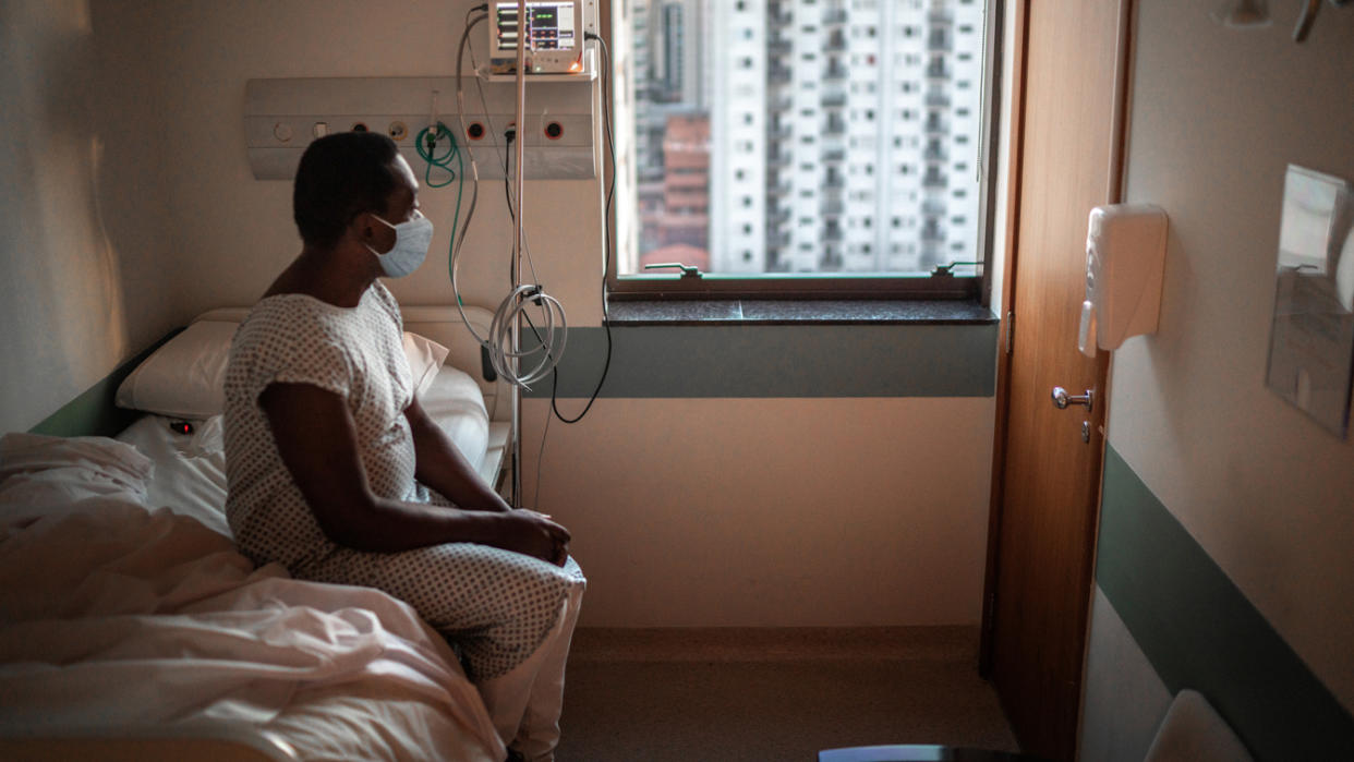 A Black woman waits on a hospital bed in a high-rise. (Getty Images)