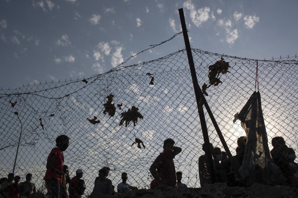 Migrants arrive a temporary camp near Mytilene town, on the northeastern island of Lesbos, Greece, Saturday, Sept. 12, 2020. Greek authorities have been scrambling to find a way to house more than 12,000 people left in need of emergency shelter on the island after the fires deliberately set on Tuesday and Wednesday night gutted the Moria refugee camp. (AP Photo/Petros Giannakouris)