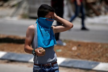 Palestinian boy holds stones during clashes with Israeli forces at a protest against Bahrain's workshop for U.S. peace plan, near Hebron, in the Israeli-occupied West Bank