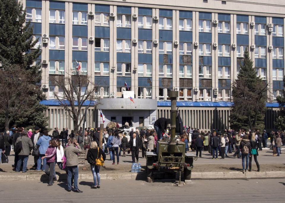 Pro-Russian activists gather in front of an entrance of the Ukrainian regional office of the Security Service in Luhansk, 30 kilometers (20 miles) west of the Russian border, in Ukraine, Tuesday, April 8, 2014. The Donetsk and Kharkiv regions and a third Russian-speaking city besieged by pro-Moscow activists over the weekend, Luhansk have a combined population of nearly 10 million out of Ukraine's 46 million, and account for the bulk of the country's industrial output. (AP Photo/Igor Golovniov)