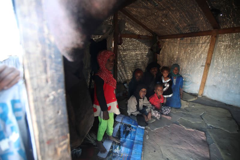 Woman and her children are pictured inside their hut at a camp for internally displaced people in Khamir of the northwestern province of Amran