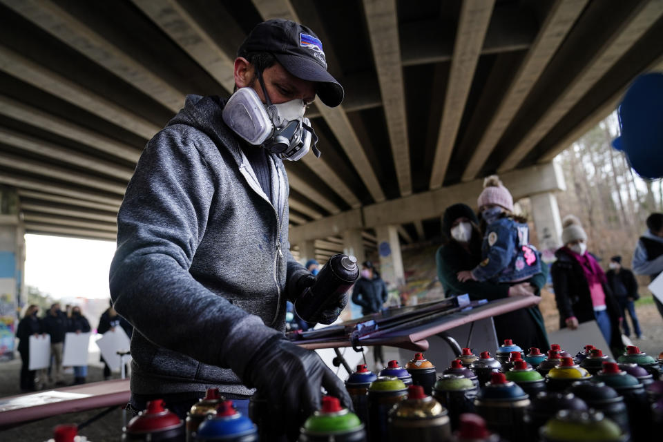 Artist Brandon Litman looks for a color to paint a U.S. Senator-elect Jon Ossoff, D-Ga., campaign poster for voters waiting in line after Georgia's Senate runoff race on Sunday, Jan. 10, 2021, in Atlanta. (AP Photo/Brynn Anderson)