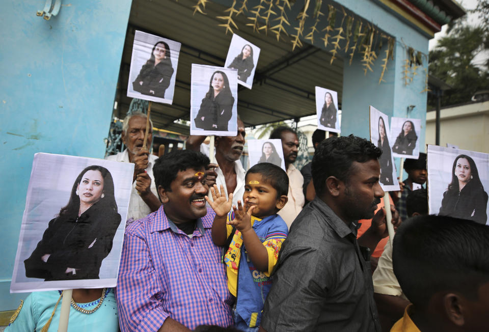 FILE - In this Jan. 20, 2021, file photo, a child reacts as villagers hold placards featuring Vice President Kamala Harris after participating in special prayers ahead of the inauguration, outside a Hindu temple in Thulasendrapuram, the hometown of Harris' maternal grandfather, south of Chennai, Tamil Nadu state, India. (AP Photo/Aijaz Rahi, File)