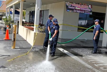 Fort Myers firefighters wash stains with bleach and a firehose in the parking lot of Club Blu after a shooting in Fort Myers, Florida, U.S. July 25, 2016. REUTERS/Joe Skipper