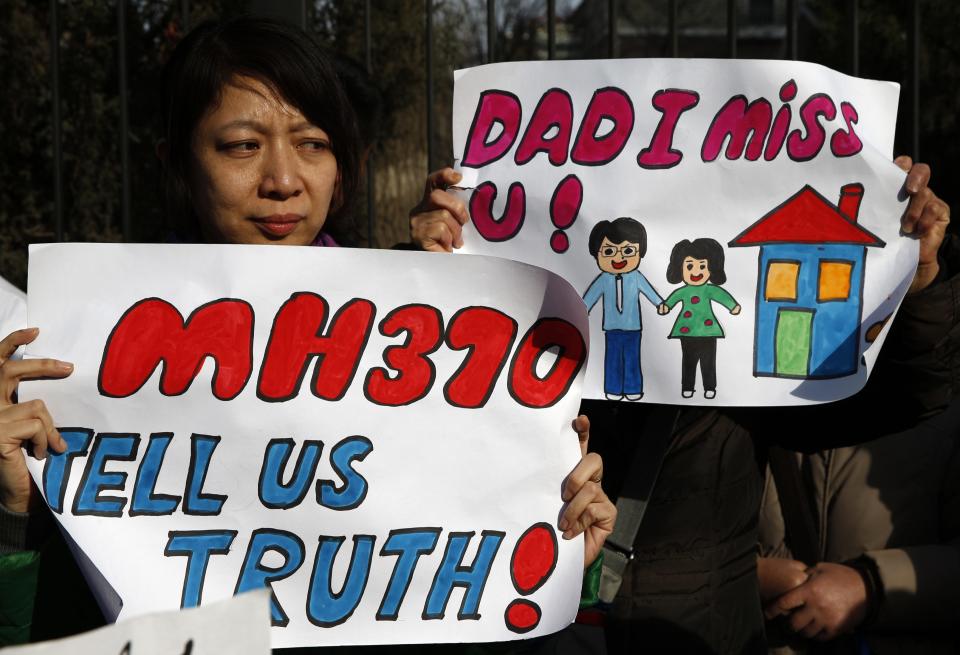 Catherine Gang, whose husband Li Zhi was onboard the missing Malaysia Airlines flight MH370, holds a sign during a gathering outside the Malaysian embassy in Beijing