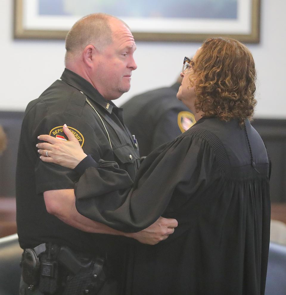 Summit County Sheriff's Deputy John Lombardo talks Thursday with Judge Kathryn Michael after giving a statement about being in a cruiser that was rammed at high speed by Mark Carlson, who was sentenced to prison for kidnapping three children and carjacking two vehicles.