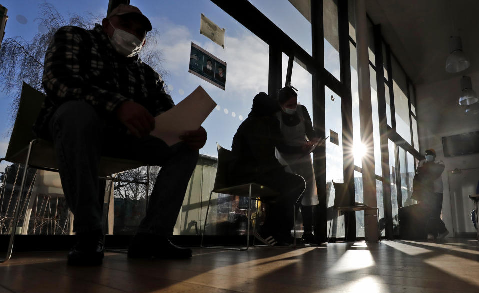 Homeless people wait socially distanced for their dose of the AstraZeneca vaccine at the Welcome Centre in Ilford, east London, Friday, Feb. 5, 2021. (AP Photo/Frank Augstein)