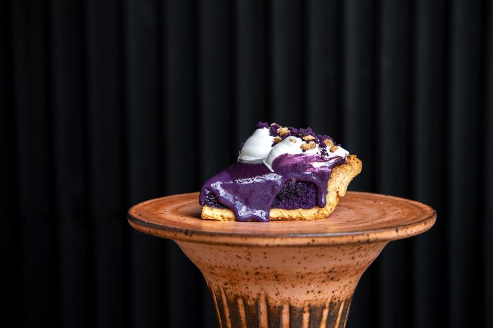 A slice of purple ube pie on a pedestal.