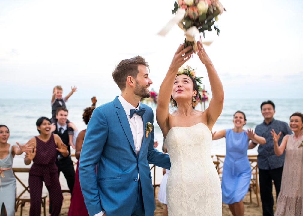 couple at wedding on the beach throwing bouquet