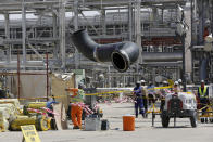 In this photo opportunity during a trip organized by Saudi information ministry, workers replace a damaged tube in the Aramco's Khurais oil field, Saudi Arabia, Friday, Sept. 20, 2019 after it was hit during Sept. 14 attack. Saudi officials brought journalists Friday to see the damage done in an attack the U.S. alleges Iran carried out. Iran denies that. Yemen's Houthi rebels claimed the assault. (AP Photo/Amr Nabil)