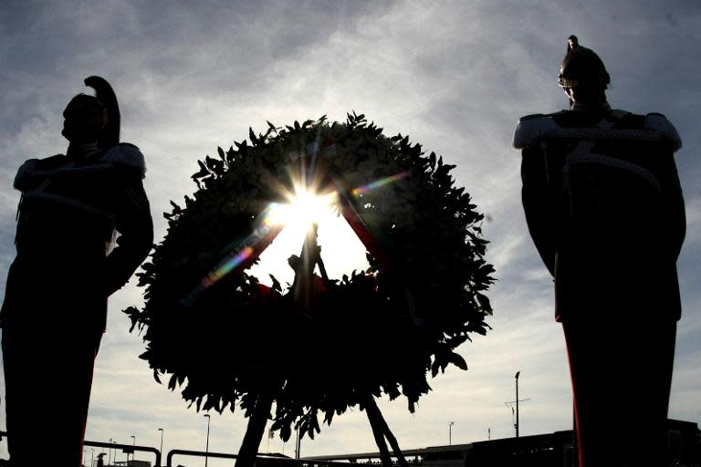 Italian presidential guardsmen stand at attention on October 21, 2013 on San Leone pier in the southern Sicilian city of Agrigento during a ceremony commemorating the migrants who drowned off the southern Italian island of Lampedusa