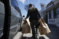 -FILE - In this March 15, 2018 file photo, an undercover Los Angeles County sheriff's deputy loads two evidence bags into a van after raiding an illegal marijuana dispensary in Compton, Calif. An unwelcome trend is emerging in California, as the nation's most populous state enters its fifth year of broad legal marijuana sales. Industry experts say a growing number of license holders are secretly operating in the illegal market working both sides of the economy to make ends meet. (AP Photo/Jae C. Hong, File)