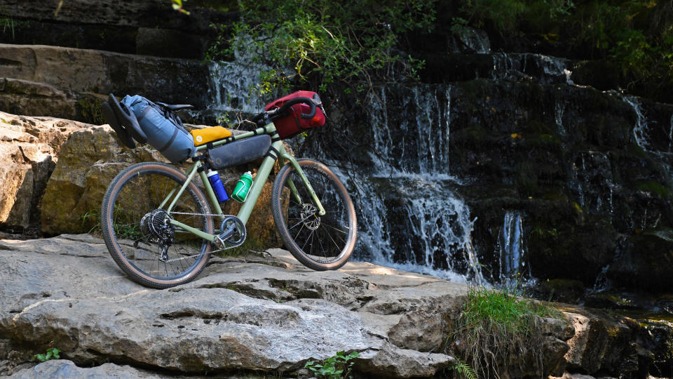 A bike set up for bikepacking in front of a waterfall