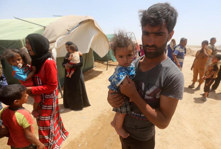 Iraqi families who fled the city of Ramadi after it was seized by Islamic State (IS) militants, gather during a sand storm at a camp for internally displaced in Amriyat al-Fallujah, on May 22, 2015