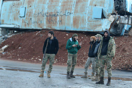 Rebel fighters stand near a damaged bus used as a barricade in the rebel-held besieged Bab al-Hadid neighbourhood of Aleppo, Syria December 2, 2016. The graffiti on the bus reads in Arabic: "Aleppo is tired mother...19/10/2016 and we still want freedom." REUTERS/Abdalrhman Ismail