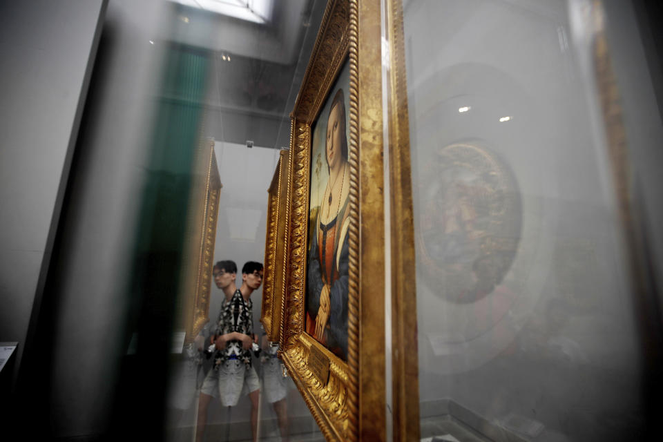 A visitor is reflected through a glass case as he admires Italian Renaissance master Raphael's 1506 portrait of noblewoman Maddalena Doni, at the Uffizi Gallery museum, in Florence, Italy, Tuesday, Aug. 6, 2019. With the paintings safely behind nearly invisible barriers, no annoying ropes need separate visitors from the paintings, and, to Uffizi Gallery director Eike Schmidt’s delight, museum-goers press their noses right up against the climate-controlled display cases. (AP Photo/Luca Bruno)