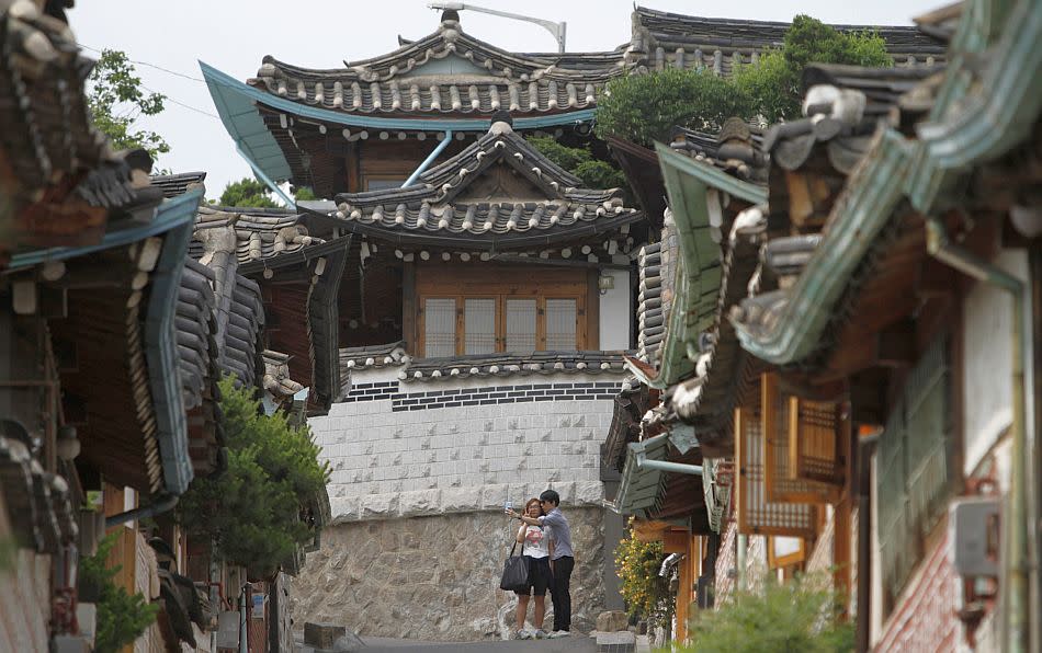 A couple takes a picture at Bukchon Hanok Village, a traditional village in Seoul. From busy lanes along the feet of skyscrapers and a throng of commuters armed with cutting edge technology, to shamanistic shrines and grand palaces, Seoul - a city of ten million - is an amalgamation of a modern high-tech metropolis retaining the legacy of age old traditions.