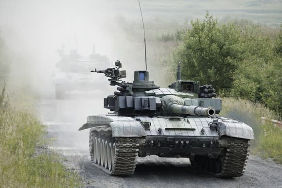 Military tanks on a dusty road.