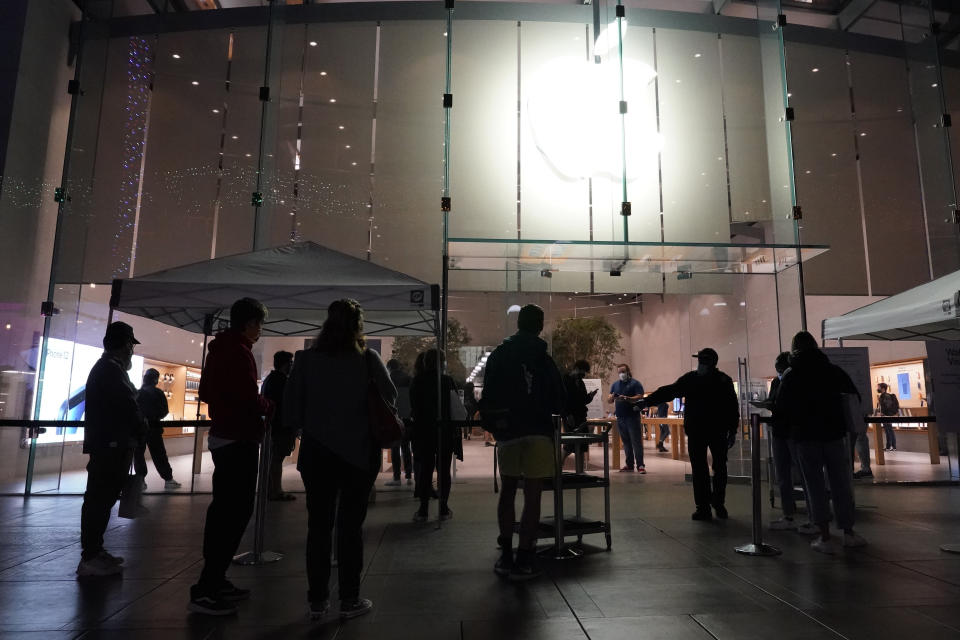 Shoppers wait outside an Apple Store on Thursday, Nov. 19, 2020, in Santa Monica, Calif. California Gov. Gavin Newsom is imposing an overnight curfew as the most populous state tries to head off a surge in coronavirus cases. On Thursday, Newsom announced a limited stay-at-home order effective Saturday night in 41 counties that account for more than 90 percent of the state's population. (AP Photo/Marcio Jose Sanchez)