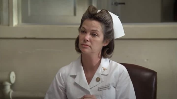 Louise Fletcher as Nurse Ratched looking at someone intently in the film One Flew Over the Cuckoo's Nest.