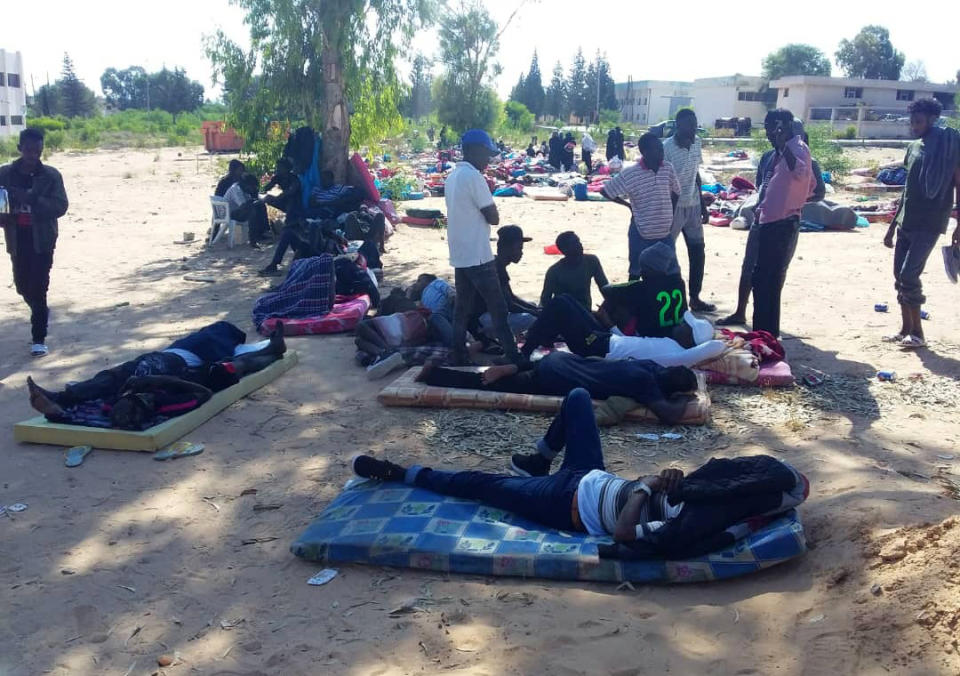 In this image taken on a mobile phone on Wednesday July 3, 2019, people rest outside at the detention center in Tripoli's Tajoura neighborhood. Libyan officials say an airstrike has struck the detention center for migrants in the capital, killing at least 40 people and wounding dozens. The airstrike was likely to raise further concerns about the European Union's policy of partnering with Libyan militias to prevent migrants from crossing the Mediterranean, which often leaves them at the mercy of brutal traffickers or stranded in squalid detention centers near the front lines. (AP Photo)