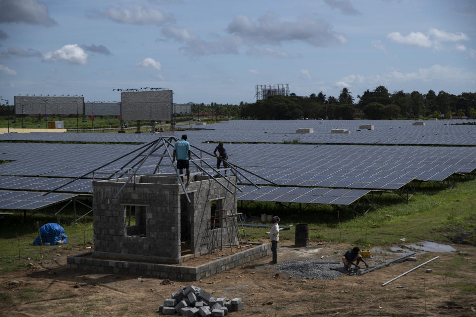 Workers build a temporary structure next to solar panels at the Cochin International airport in Kochi, Kerala state, India, Thursday, Aug. 25, 2022. India’s renewables sector is booming, with the country projected to add 35 to 40 gigawatts of renewable energy annually until 2030, enough to power up to 30 million more homes each year, a report said on Thursday, Oct. 13. (AP Photo/R S Iyer)