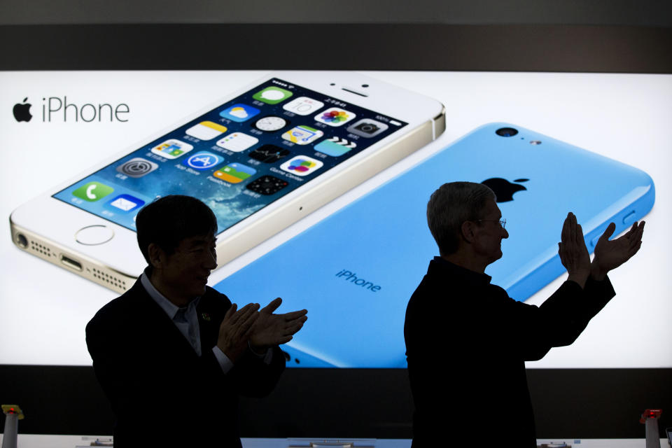 FILE - In this Jan. 17, 2014 file photo, Apple CEO Tim Cook, right, and China Mobile's chairman Xi Guohua are silhouetted against a screen showing iPhone products as they applaud during a promotional event that marks the opening day of sales of China Mobile's 4G iPhone 5s and iPhone 5c in Beijing, China. A California jury determined Friday May 2, 2014, that Samsung infringed Apple smartphone patents and awarded $120 million damages. (AP Photo/Alexander F. Yuan, File)