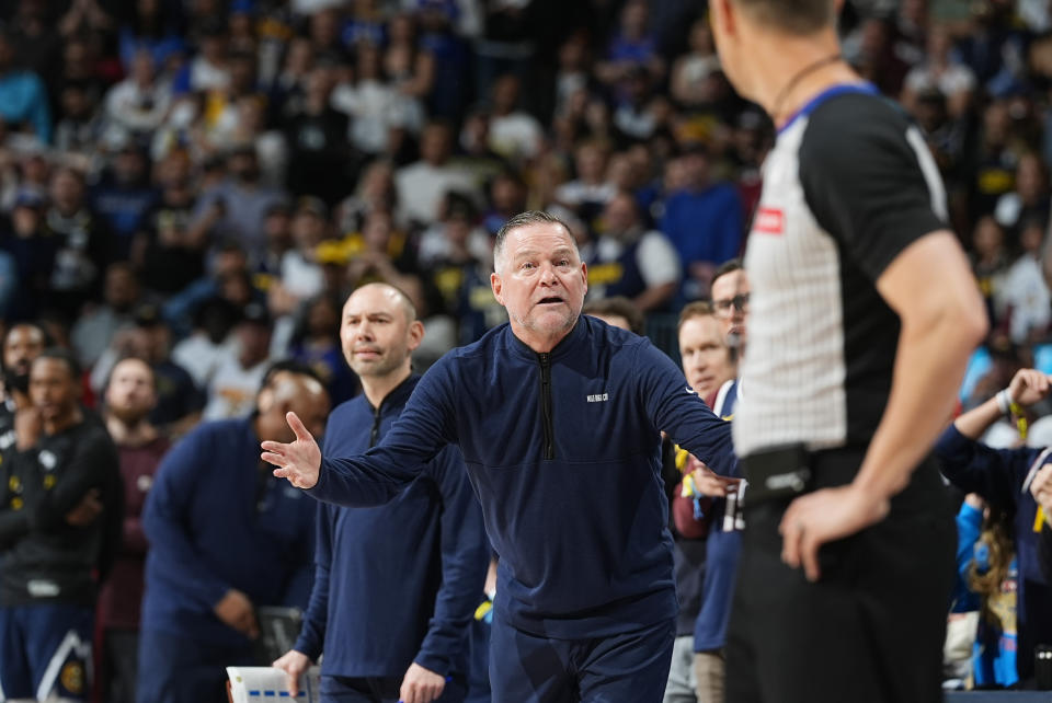 Denver Nuggets head coach Michael Malone, center, argues for a call with referee Kevin Scott in the second half of Game 5 of an NBA basketball first-round playoff series against the Los Angeles Lakers Monday, April 29, 2024, in Denver. (AP Photo/David Zalubowski)