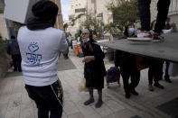 A volunteer assists as several dozen impoverished elderly Israelis, many of them Holocaust survivors, gather for distribution of food aid and cold weather supplies by the Chasdei Naomi charity, ahead of International Holocaust Remembrance Day in Jerusalem, Wednesday, Jan. 26, 2022. Thursday marks the 77th anniversary of the liberation of the Nazi’s Auschwitz-Birkenau death camp in Poland. (AP Photo/Maya Alleruzzo)