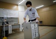 A member of Election Management Committee wearing a protective face mask and vinyl gloves disinfect a ballot box amid the coronavirus disease (COVID-19) outbreak, at a voting station for the Tokyo Governor election in Tokyo