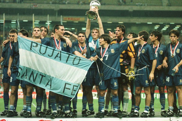 Festejo argentino tras vencer en la final de Malasia 97 a Uruguay; Esteban Cambiasso levanta el trofeo de campeón mundial y Scaloni lleva la bandera de su Pujato natal
