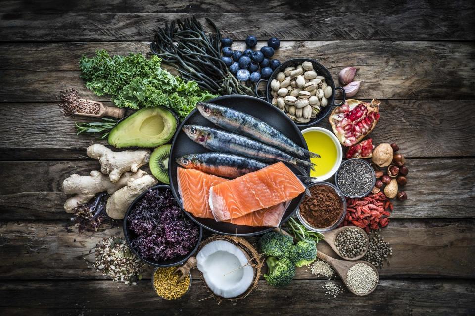 top view of healthy, antioxidant group of food placed at the center of a rustic wooden table the composition includes food rich in antioxidants considered as a super food like avocado, kale, blueberries, chia seeds, coconut, broccoli, different nuts, salmon, sardines, pollen, quinoa, hemp seeds, seaweed, cocoa, olive oil, goji berries, flax seeds, kiwi fruit, pomegranate and ginger xxxl 42mp studio photo taken with sony a7rii and zeiss batis 40mm f20 cf