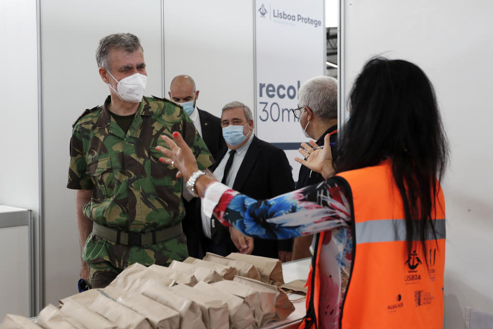 A volunteer at a vaccination center greets Rear Admiral Henrique Gouveia e Melo as he arrives at the center in Lisbon, Saturday, Sept. 11, 2021. As Portugal nears its goal of fully vaccinating 85% of the population against COVID-19 in nine months, other countries want to know how it was able to accomplish the feat. A lot of the credit is going to Gouveia e Melo. (AP Photo/Armando Franca)