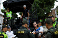 An undocumented Venezuelan woman, carrying her son, talks with Colombian police officers before being deported to Venezuela during a raid in Villa del Rosario, Colombia August 24, 2018. REUTERS/Carlos Garcia Rawlins