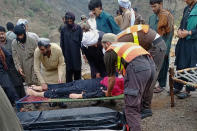 In this photo provided by the Baluchistan Rescue Department, rescue workers and volunteers remove a body after it was recovered from the wreck of a passenger bus that slid off mountain road and fell into a deep ravine, in Zhob, Baluchistan province, in southwest Pakistan, Sunday, July 3, 2022. An official said the passenger bus slid off a mountain road and fell 200 feet (61 meters) into a ravine in heavy rain killing at least 18 people and injuring some 12 others. (Baluchistan Rescue Department via AP)