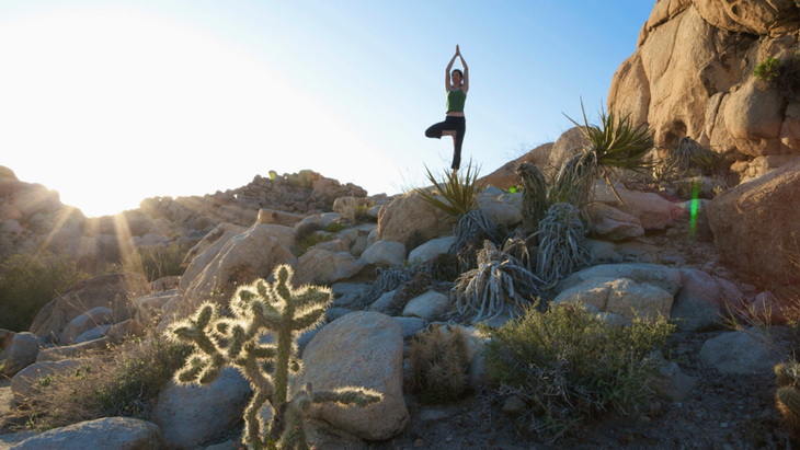 Woman practicing yoga on a rock in Joshua Tree Park