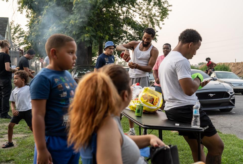 Dwayne Taylor, center, of Lincoln Park, gets food off the grill while waiting for the next match to start during a Pick Your Poison Detroit event in Detroit's Delray neighborhood on Sunday, July 18, 2021. "I'm trying to get the community out together. I'm not trying to charge anybody anything. Free food, free everything," said Taylor.