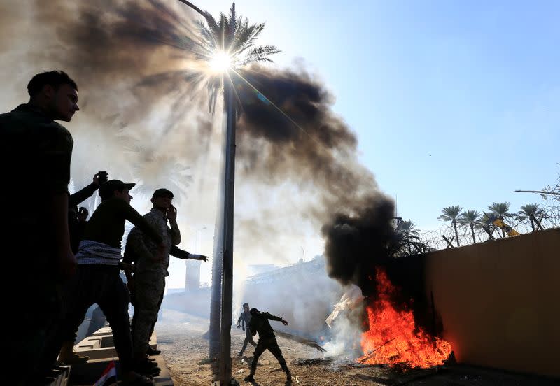 Hashd al-Shaabi fighters set fire on the U.S. Embassy wall to condemn air strikes on their bases, in Baghdad