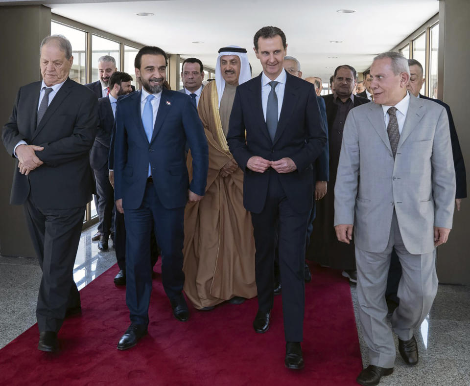 In this photo released by the official Telegram account of the Syrian Presidency, Syrian President Bashar Assad, second right, walks with a delegation representing various Arab parliaments in Damascus, Sunday, Feb. 26, 2023. (Syrian Presidency via Telegram via AP)